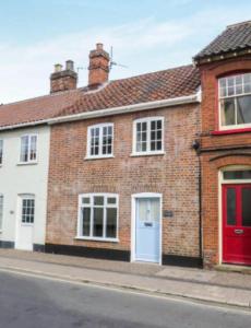 una casa de ladrillo con puertas rojas en una calle en A quaint Wymondham cottage, en Norwich