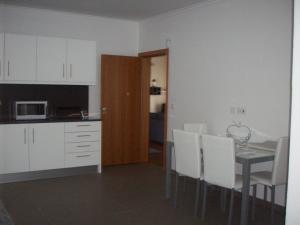 uma cozinha e sala de jantar com mesa e armários brancos em Casa Santos em Prazeres