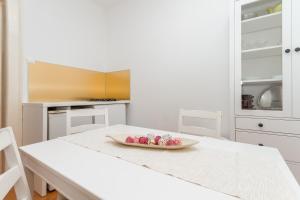 eine weiße Küche mit einem Tisch und einer Obstschale darauf in der Unterkunft Apartment Petka in Piran