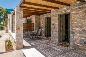 een patio met een stenen gebouw met stoelen erop bij Petras Gi - Stone Houses in Stoupa