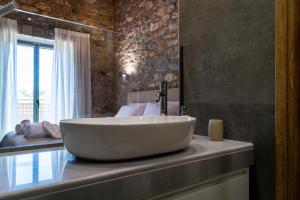 La salle de bains est pourvue d'un grand lavabo blanc sur un comptoir. dans l'établissement Petras Gi - Stone Houses, à Stoupa
