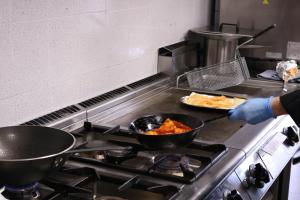 a person cooking food on a stove in a kitchen at El Sueño del Infante in Guadalajara