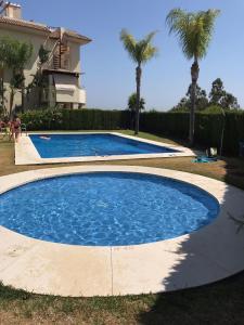 una grande piscina con acqua blu in un cortile con palme di MARBELLA,ESTEPONA,SELWO HILLS,Sea and Sun Hills,NEW GOLDEN MILES a Estepona
