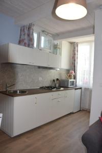 una cocina con armarios blancos y fregadero en Petite maison en Negrar