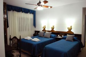 two beds in a room with blue sheets at Hotel Berlin in Gualeguaychú