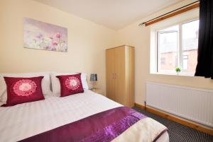 a bedroom with a bed with red pillows and a window at No 10 LimeHouse in Oldham