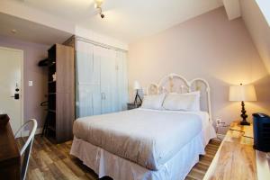1 dormitorio con 1 cama blanca y suelo de madera en The Palmerston, en Toronto