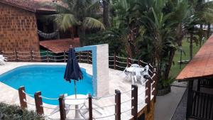 a pool with an umbrella and a fence around it at Condomínio frente ao mar in Boicucanga