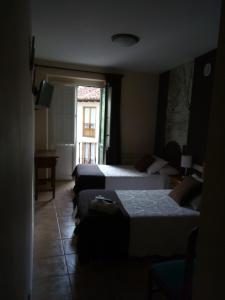 a hotel room with three beds and a window at Casa Favila in Potes