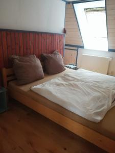un letto con lenzuola e cuscini bianchi in una stanza di Ferienwohnung Warderhof a Sandstedt