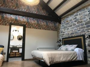 ein Schlafzimmer mit einem Bett und einer Steinmauer in der Unterkunft Hostel-Albergue Monte Perdido in Torla-Ordesa