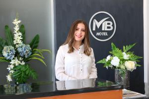 a woman is standing behind a counter with flowers at Hotel MB in Campeche