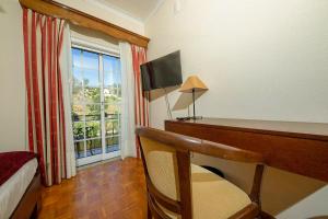 a bedroom with a desk with a computer and a window at Hotel Beira Dão in São Gemil