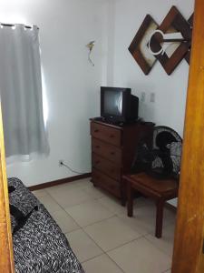 Habitación con TV en un tocador con silla en Resort Villa da praia apto 30 arraial do cabo en Arraial do Cabo