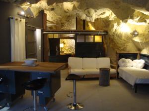 ein Wohnzimmer mit einem Bett, einem Tisch und einer Theke in der Unterkunft La Grotte du Moulin in Noyers-sur-Cher