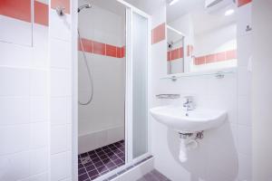 y baño blanco con lavabo y ducha. en Domov mládeže - Ubytování Sokolov en Sokolov