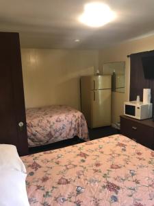 a hotel room with two beds and a refrigerator at Evergreen Motel in Oswego