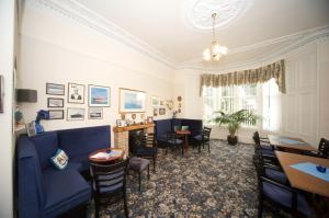 a dining room with a blue couch and chairs at Dellwood Hotel in Campbeltown
