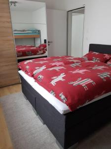 um quarto com uma cama com um cobertor vermelho com cavalos em Primel (385 Sw) Whg. Manuela em Tiefencastel