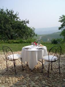 a table with a white table cloth and two chairs at Dindina Agriturismo in Neviglie