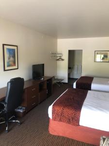 een hotelkamer met 2 bedden, een bureau en een televisie bij Yellowstone Big Rock Inn in Gardiner