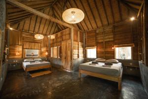 a bedroom with two beds in a wooden cabin at Musa Villas and Bungalows Gili Air in Gili Air