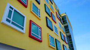 un edificio amarillo con ventanas coloridas. en Pine Garden Hotel en Kuching