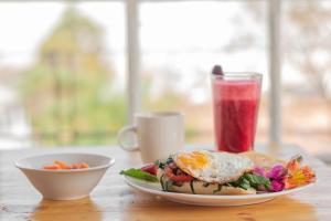 a plate of food with an egg on a sandwich and a drink at Botanico Hostel in Bogotá