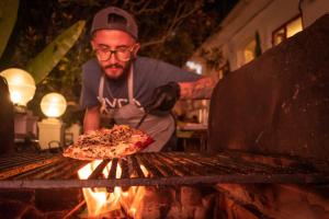 a man is making a pizza on a grill at Botanico Hostel in Bogotá