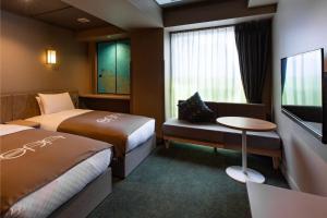 a hotel room with two beds and a flat screen tv at eph TAKAYAMA in Takayama