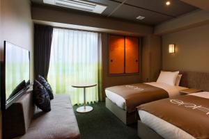 ein Hotelzimmer mit 2 Betten und einem TV in der Unterkunft eph TAKAYAMA in Takayama