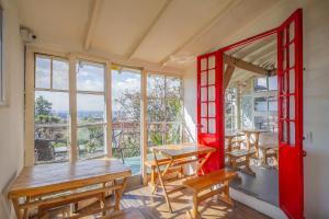 a room with tables and a red door and windows at Botanico Hostel in Bogotá