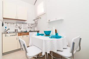 cocina blanca con mesa y sillas en Apartments Carmen & Tosca, en Dubrovnik