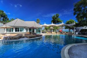 a swimming pool with chairs and umbrellas in a resort at Pattaya Discovery Beach Hotel in Pattaya
