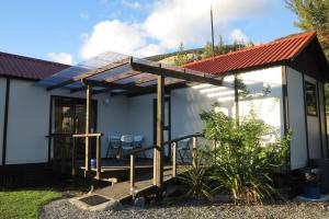 a house with a solar roof and a deck at Tophouse Mountainview Cottages in Saint Arnaud