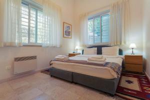 a bedroom with a large bed with two windows at Colony Suites - Emek Refaim in Jerusalem +6 photos