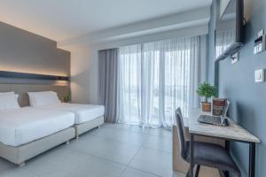 a bedroom with a bed and a desk with a laptop at Avra Hotel in Rafina