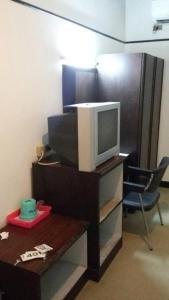 a room with a tv on a stand with a table at Queen Songkhla Hotel in Songkhla