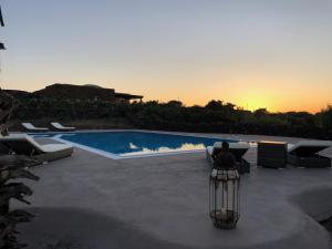 - une vue sur la piscine éclairée et le coucher du soleil dans l'établissement I Dammusini di Pantelleria, à Pantelleria