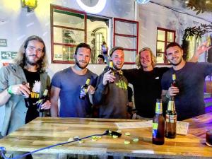 a group of men standing around a table holding bottles of beer at Botanico Hostel in Bogotá