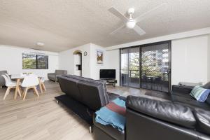 a living room with a black leather couch and a table at Breakers 3 - linen not included in Forster