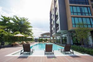 a swimming pool with chairs and umbrellas next to a building at Wellness Chiang Mai Hotel in Chiang Mai