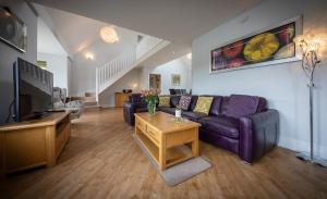 a living room with a purple couch and a tv at Karinya in Drynoch