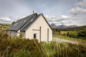 a small white house with solar panels on the roof at Karinya in Drynoch
