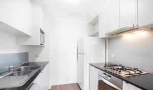 a white kitchen with a sink and a stove at ReadySet Apartments at City Tower in Melbourne