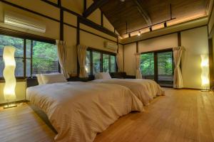 a large bedroom with two beds and windows at Villa Hamorebi in Miyajima