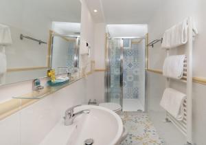 La salle de bains blanche est pourvue d'un lavabo et d'une douche. dans l'établissement Hotel Il Girasole, à Anacapri