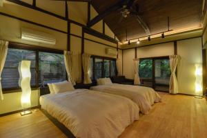 two beds in a large room with windows at Villa Hamorebi in Miyajima