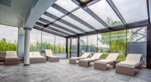 a conservatory with white chairs and windows at SPA Boutique Appartement # 26 with Indoor- and Outdoorpool in Neusiedl am See