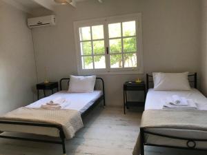 two beds in a room with a window at Athens Airport, Seaside house in Artemida